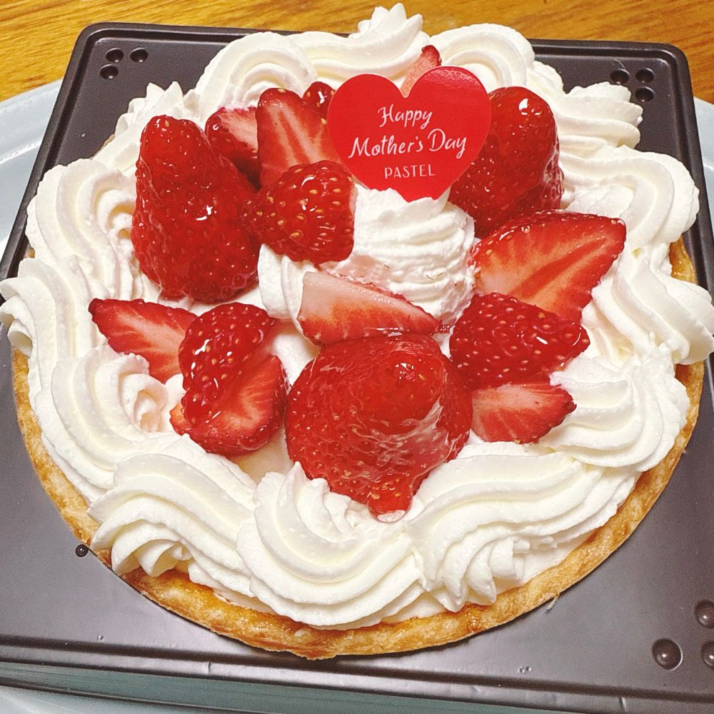 いちごタルトの写真。ホールケーキ。
丸いタルトの上にクリームとたくさんのいちごがデコレーションされている。ピックに「Happy Mother’s Day」と書かれている。