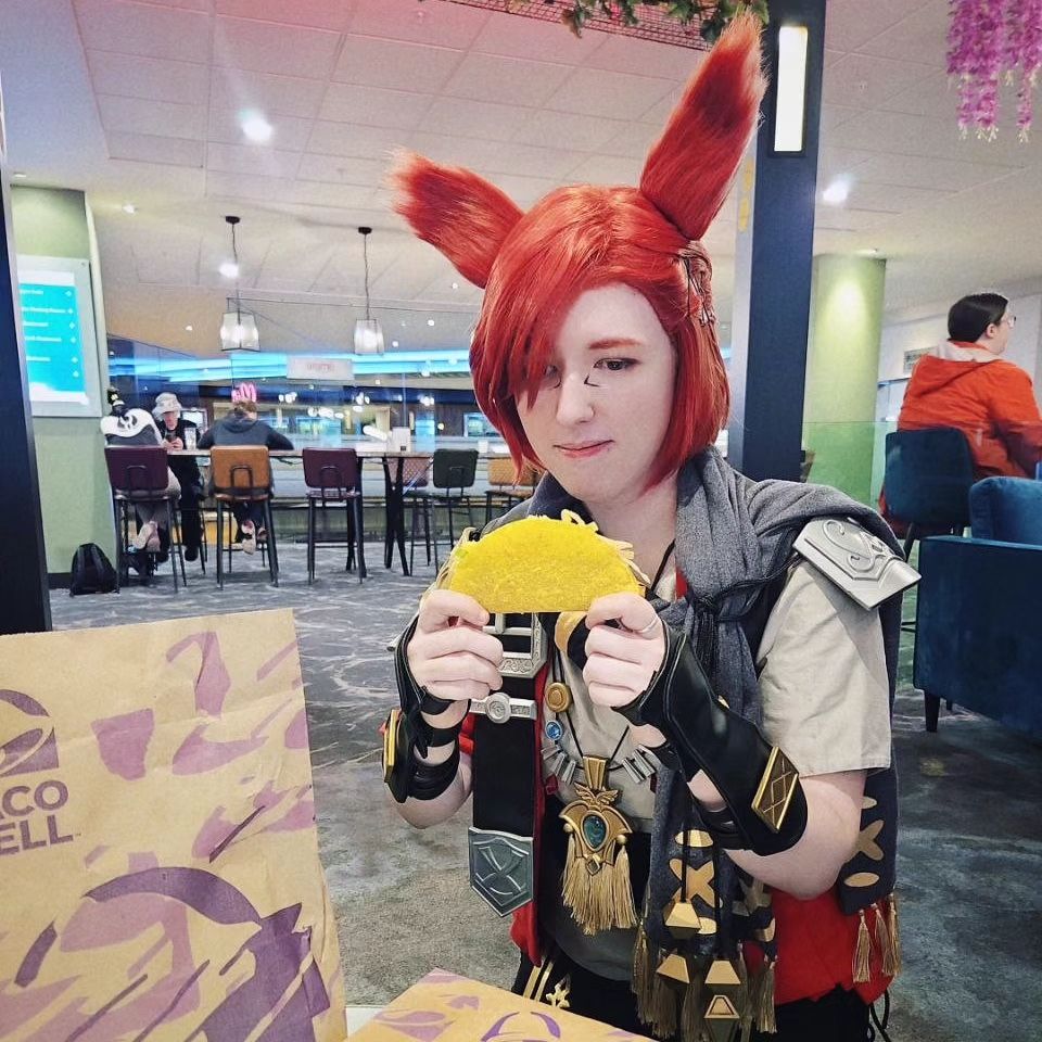 Me cosplaying G'raha Tia from Final Fantasy XIV. I'm holding a taco and somehow resisting eating it long enough for this photo.