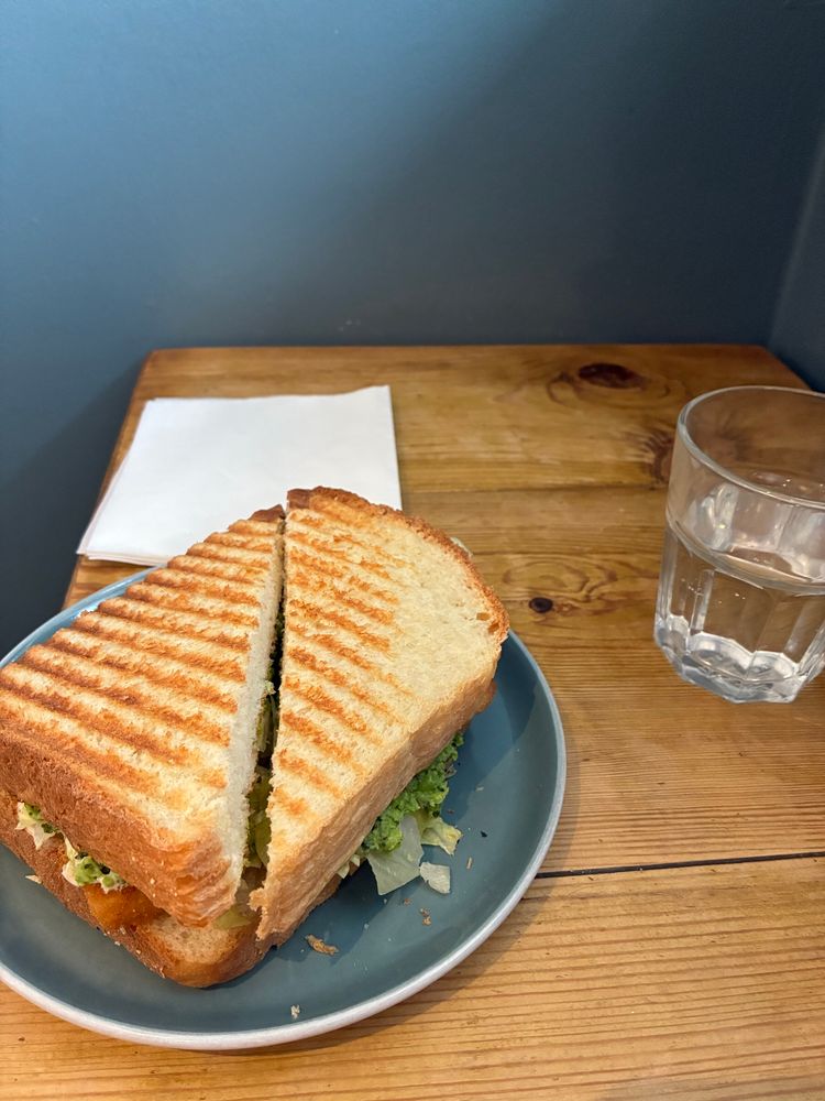 Toasted fish finger sandwich with glass of water 