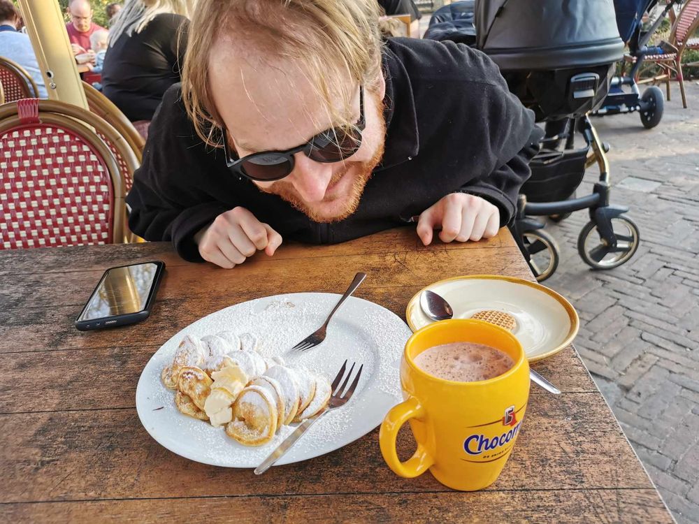 Un grand Gugusse en Polaire F.L.Y avec des lunettes de soleil (moi), qui bave devant des Poffertjes, des sortes de mini pancakes spécialité des Pays Bas, avec une tasse de Chocomel et une gaufrette.