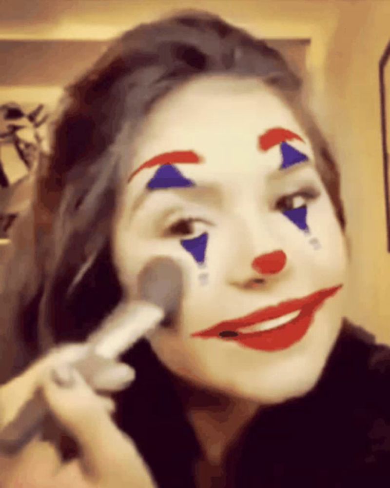 a woman with a clown face painted on her face is applying makeup