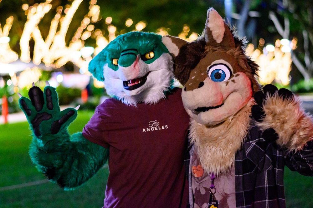 Green sergal fursuiter posing with a pony fursuiter.