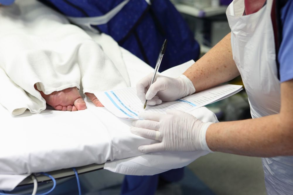 health professional writing notes with patient's foot on show 