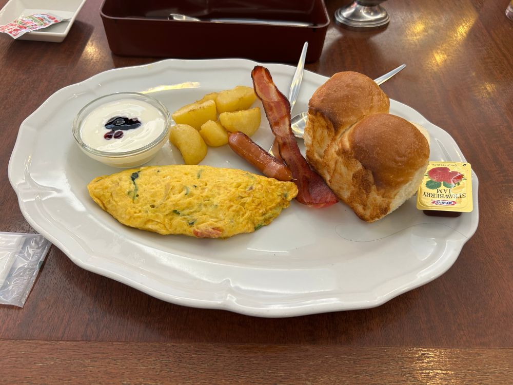 ロイヤルホストのモーニングメニューの写真
ブルーベリーソースのかかったヨーグルト、グリルポテト、カリカリベーコン、野菜オムレツ、ミニ山食パン、ジャムとバター