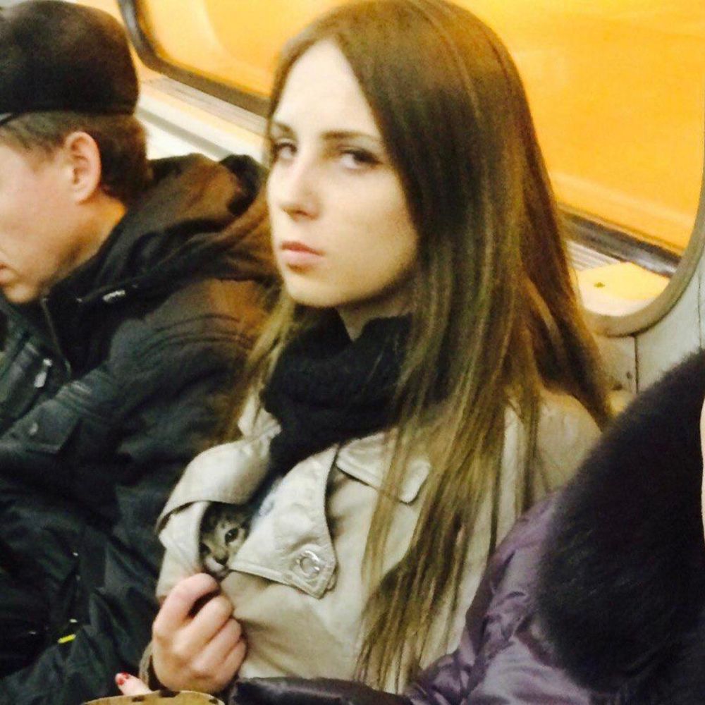 Famous picture of a woman hiding a kitten in her coat, as she is in the subway.