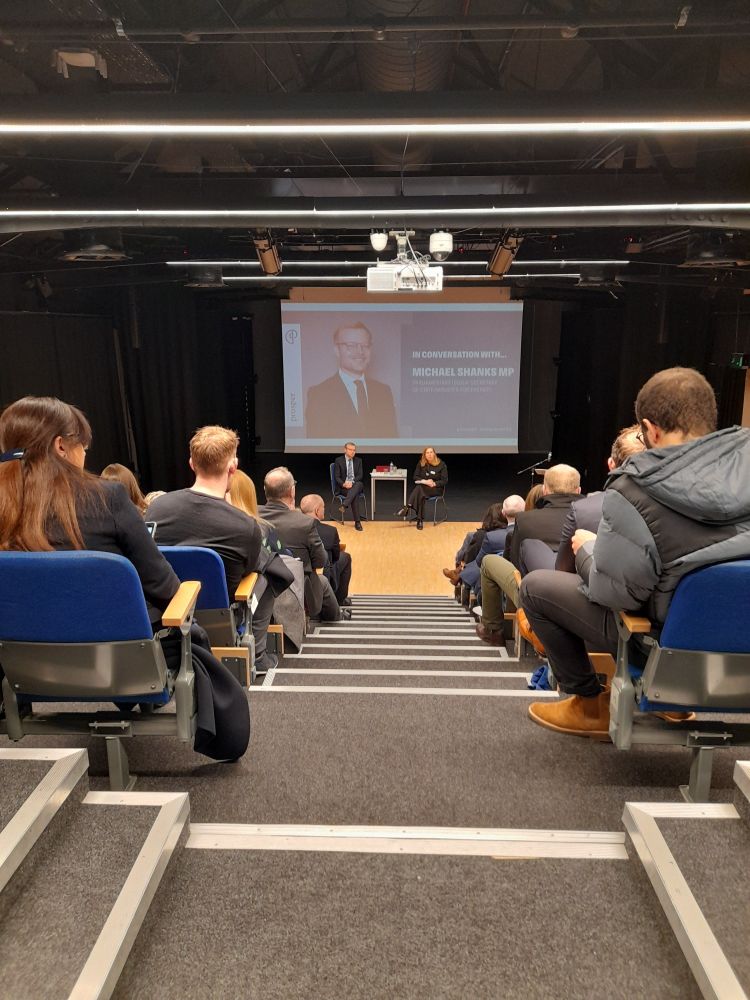 An audience looking towards a stage with Michael and Claire from Prosper holding a conversation and Q&A