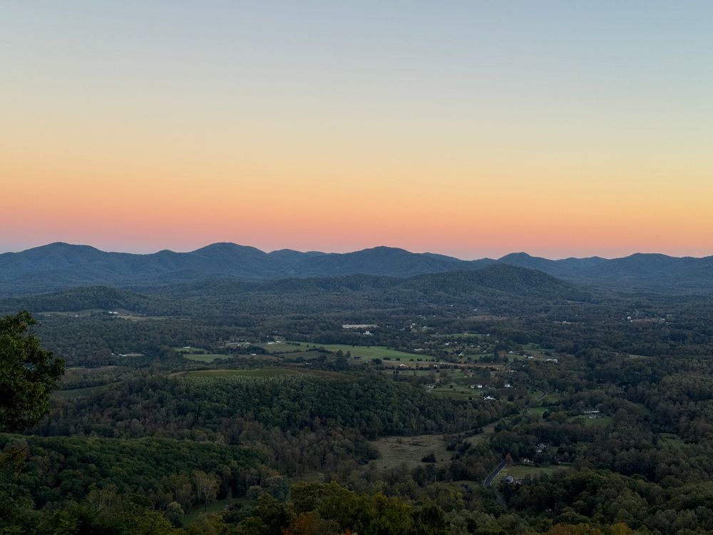 the sun setting over a valley with mountains in the distance