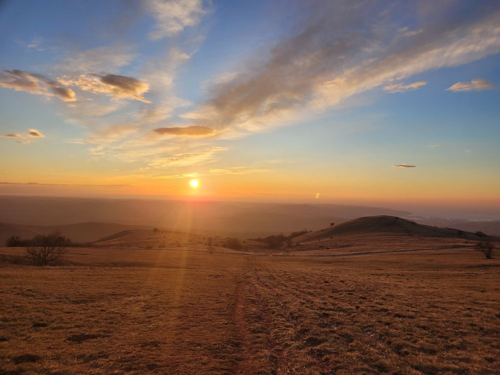 sunrays from the sunset illuminate the sky, view from the top of a hill called Slavnik, towards Koper