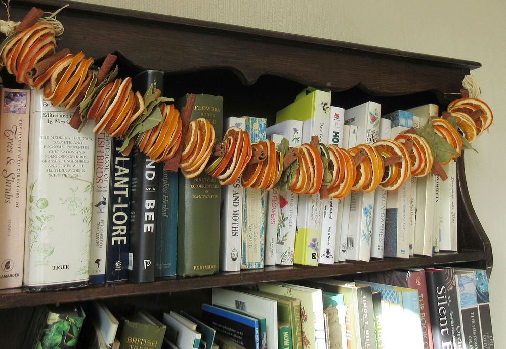 This is a picture of one of my Orange and Cinnamon Garlands.
They're made of dried slices of oranges and limes, interspersed with cinnamon sticks and bay leaves. 
This one is hung over the top shelf of our old oak dresser that I use to to house some of my natural history books but it would equally as good hanging in doorways, mantelpieces etc., (keep away from naked flames, pets and children). 