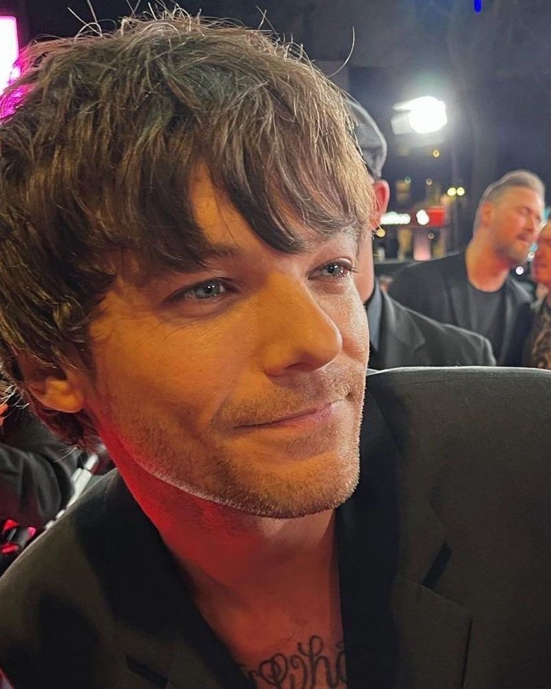 angelic photo of louis tomlinson looking off camera in a black suit