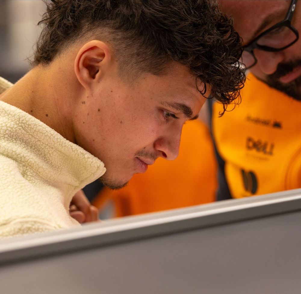 mullet lando norris in the garage looking at something with an engineer
