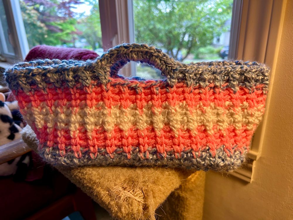 Crocheted basket in the colors and pattern of a trans pride flag