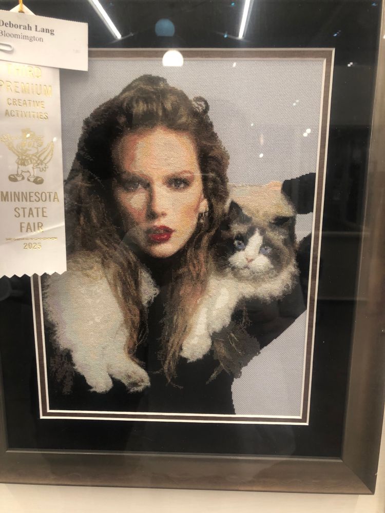 A photorealistic needlepoint of Taylor swift with her cat around her neck