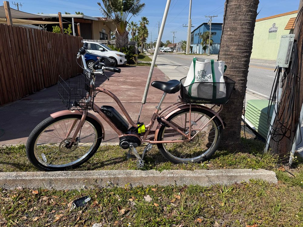 A rose pink E bike locked to a utility cable