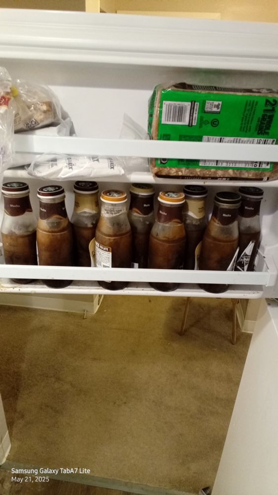 A freezer full of square  jars with a frozen brown ice 