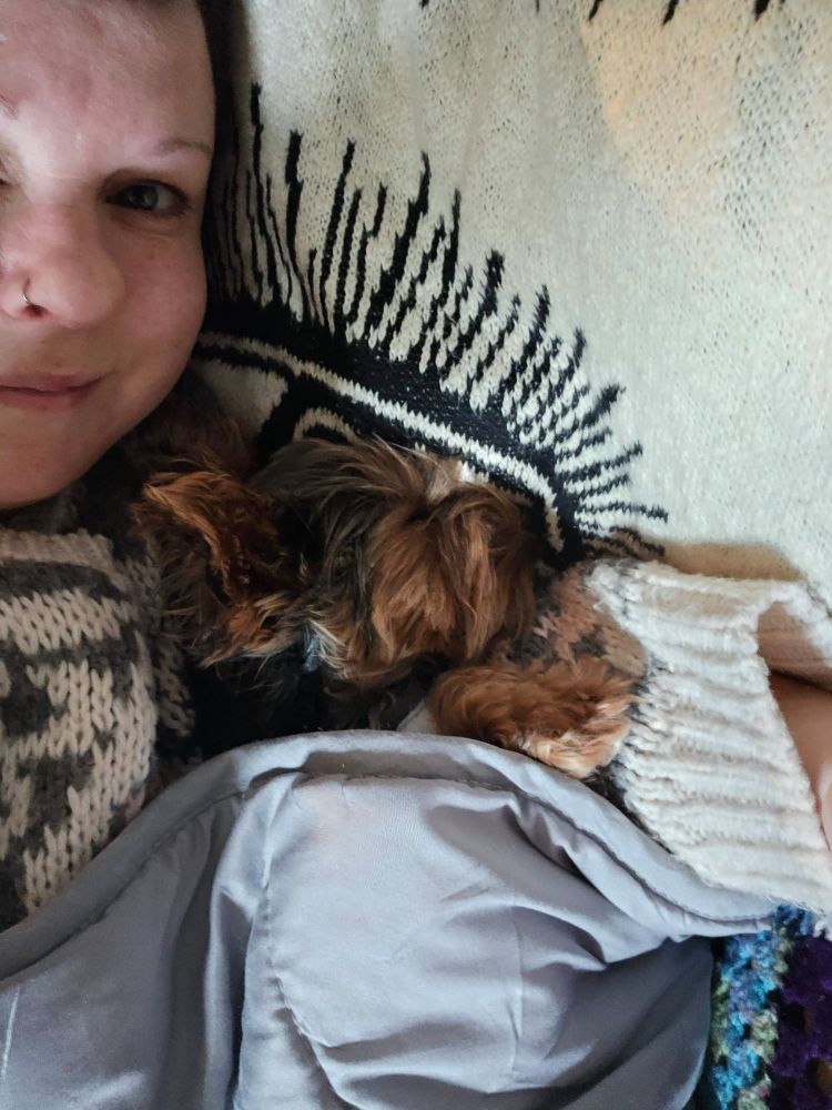 Kate is smiling contently on the left of the picture, as Tiny Toby snoozes to her right. Both are under a grey blankey. 