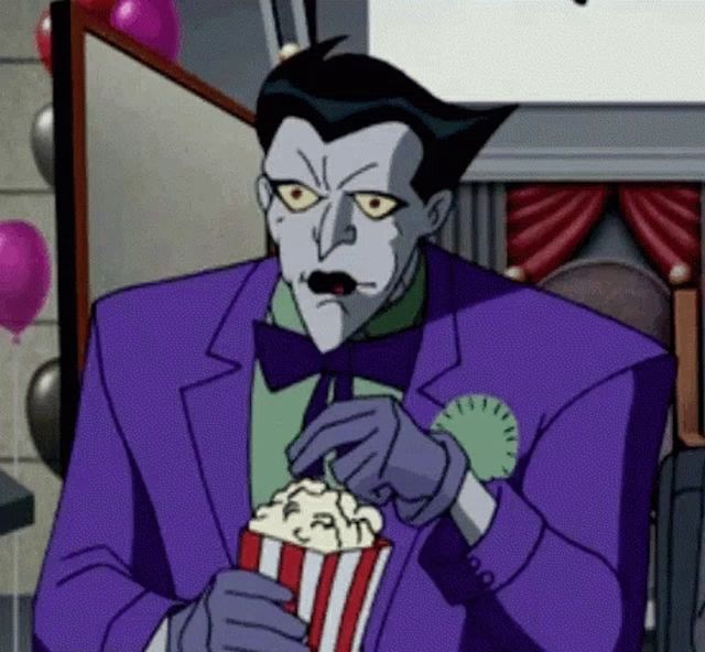 the joker from the batman animated series is eating popcorn from a popcorn bucket .