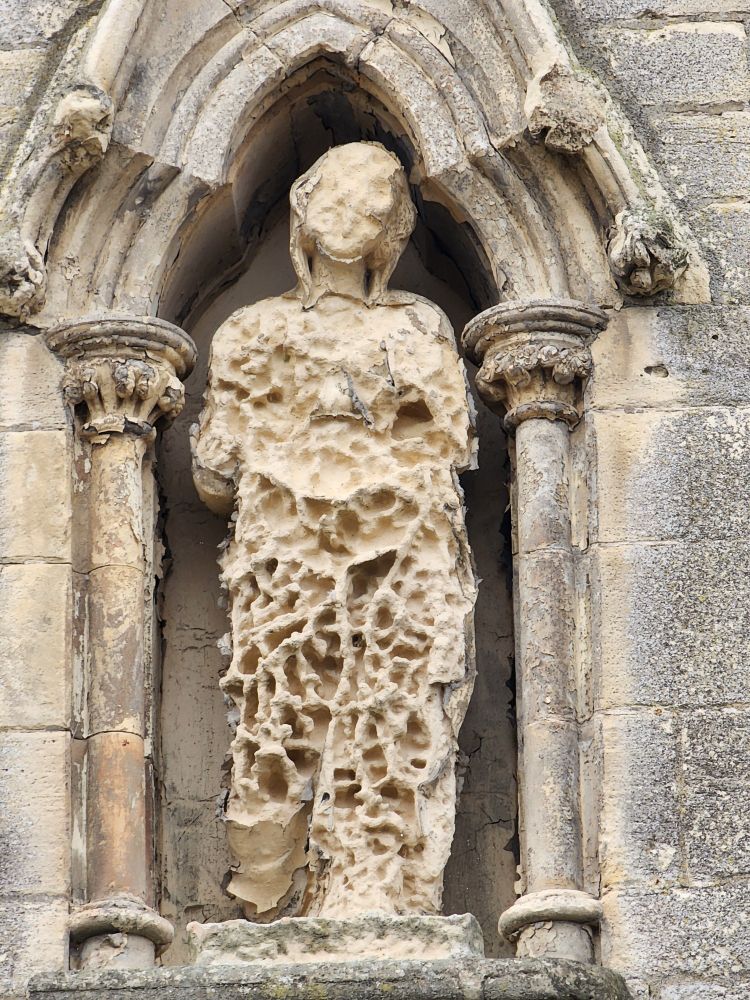 A weather-worn statue above a church door