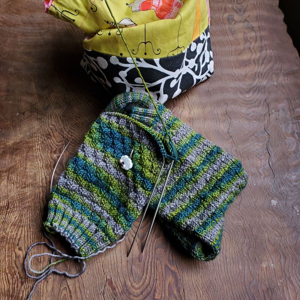 teal green and gray partially knit socks on raw wood table #knitting