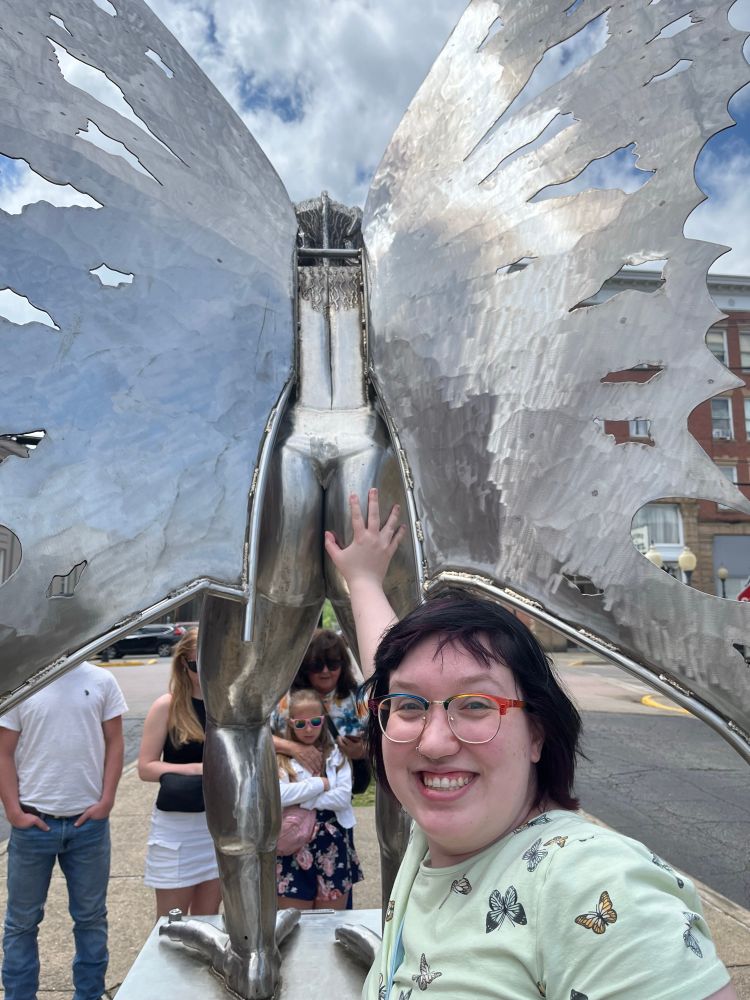 User from before smiling happily as she grabs the mothman’s statue’s ass