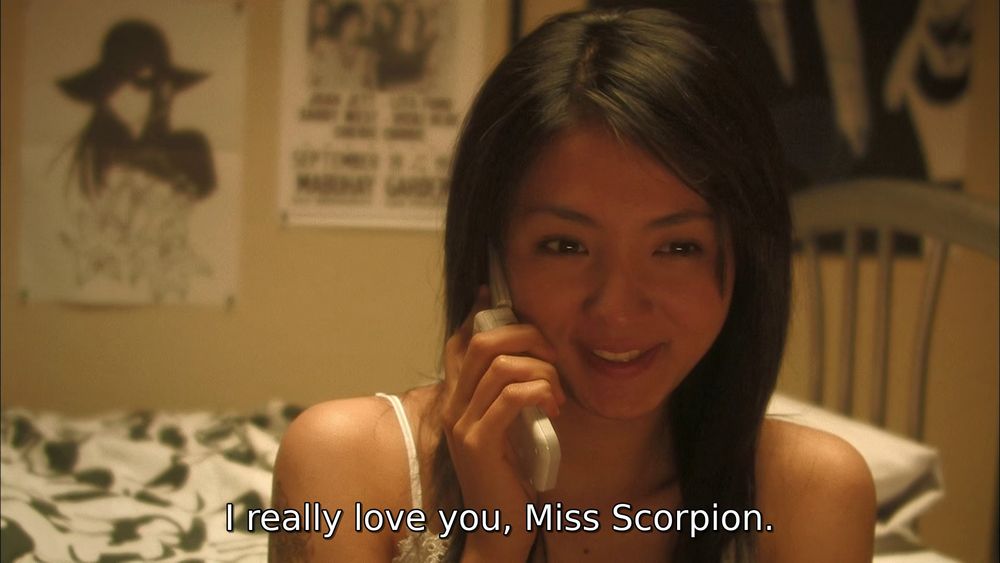 screencap of a girl smiling on the phone in her bedroom. the subtitle reads "I really love you, Miss Scorpion."