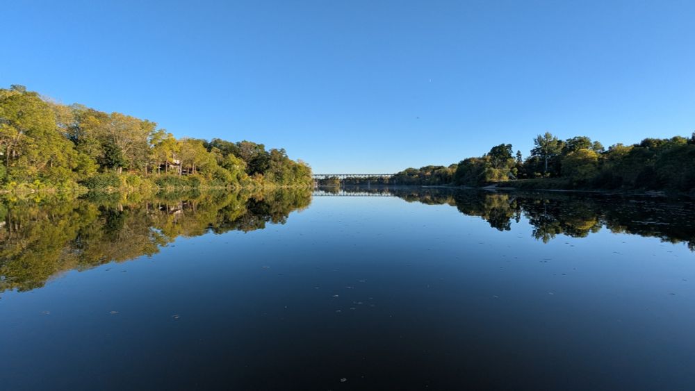 Not a ripple or cloud intrudes on a sunny downriver view of the Grand