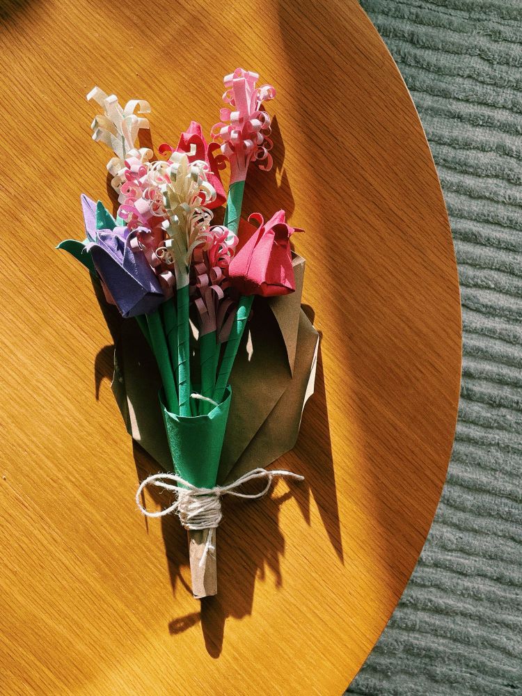 An origami flower bouquet on top of a sunlit table