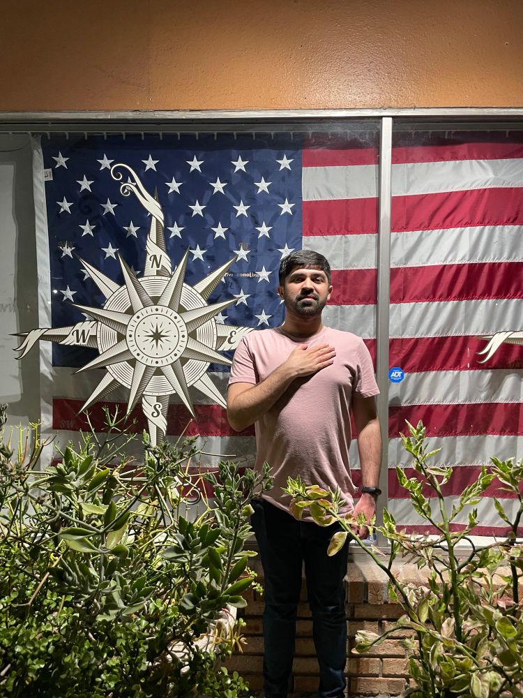 Noman with his hand over his heart in front of a fascist flag (usa)
