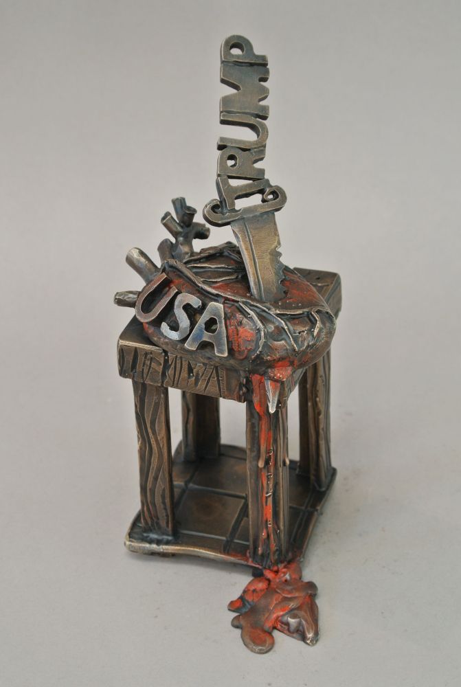 A small unique cast and fabricated bronze sculpture. Approximately 10 inches tall. It’s a heart with USA letters being stabbed by a knife with the name Trump on the handle. 
