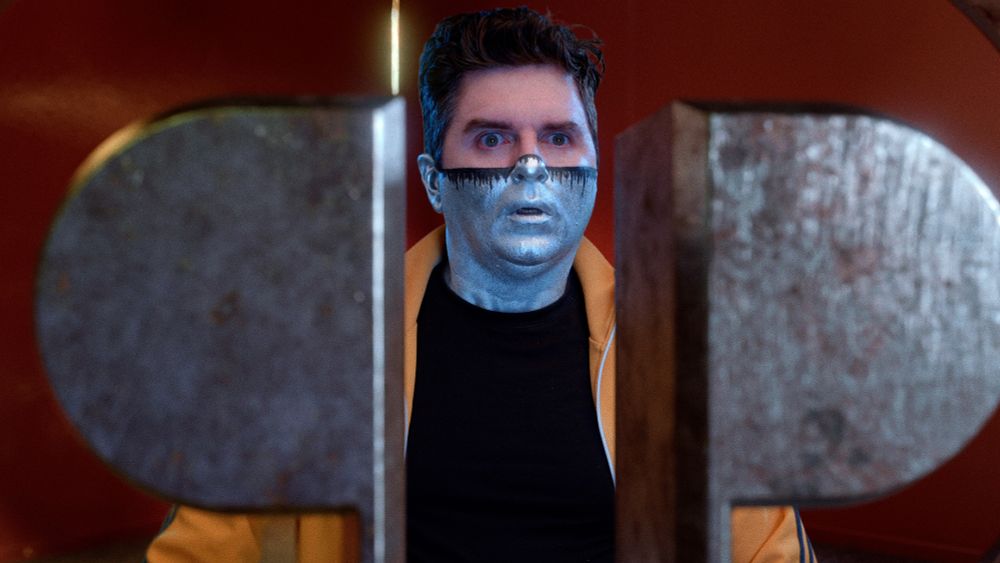 Dramatic closeup of Captain Disillusion looking through his logo-shaped window with grave concern.