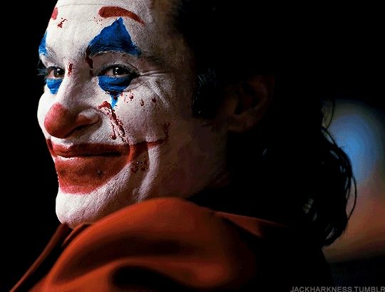 joker laughing while looking at murray’s audience; with blood on his face.