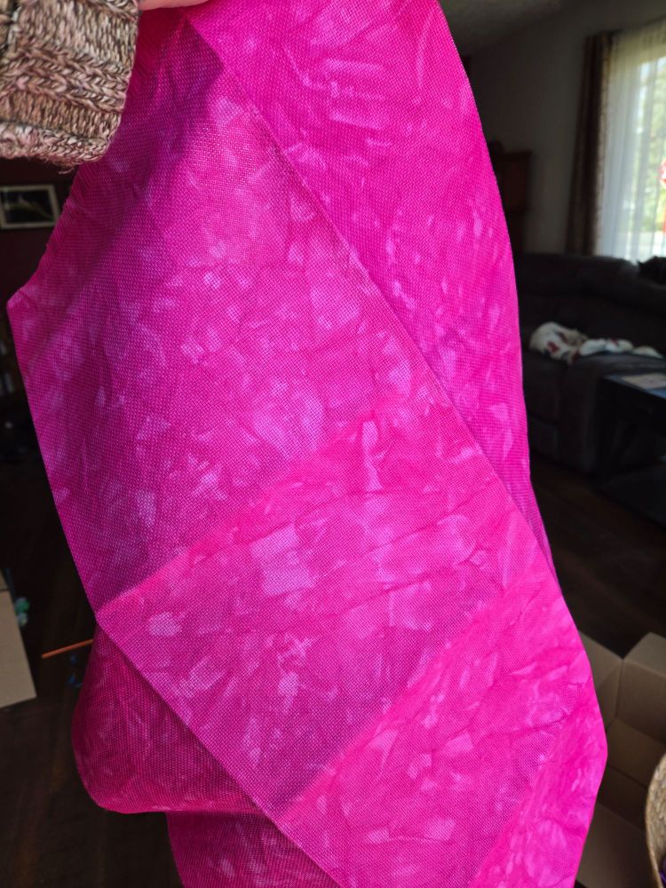 A big piece of Aida cross stitch fabric tie-dyed Barbie pink is held up