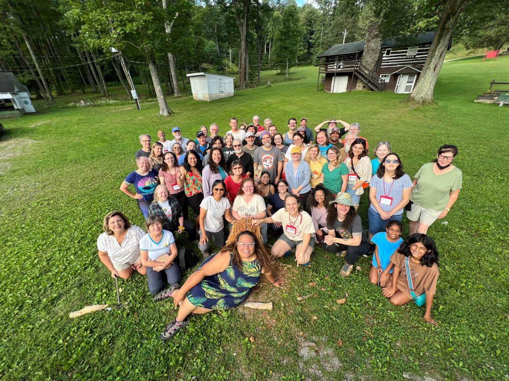 A group of several dozen people pose for a photograph in a field.