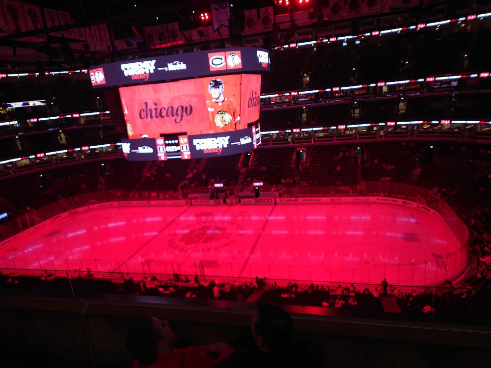 A photo of a hockey rink from the upper deck. With Blackhawks logos and red lightning.