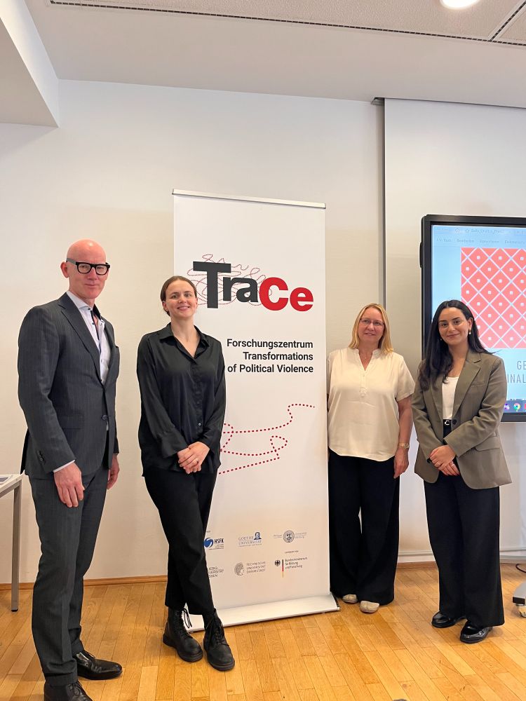 Four people stand next to a TraCe roll-up banner: A. Dirk Moses and Núrel Reitz on the left and Sabine Mannitz and Sally Ghattas on the right.