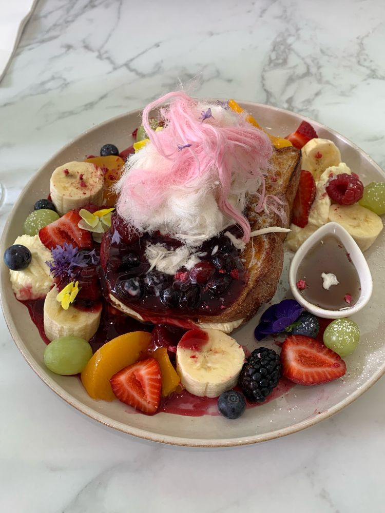 Honey bread with an assortment of fruit topped with cotton candy