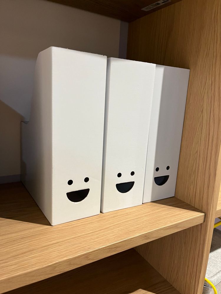 A collection of magazine holders? Or file holders? Box files? Something from Ikea anyway. They’re white and have what look like smiling faces on them
