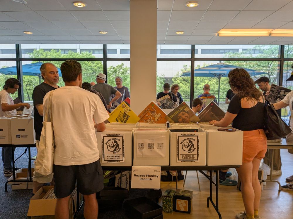 Record sale with dealers' tables with boxes of records, people happily flipping through