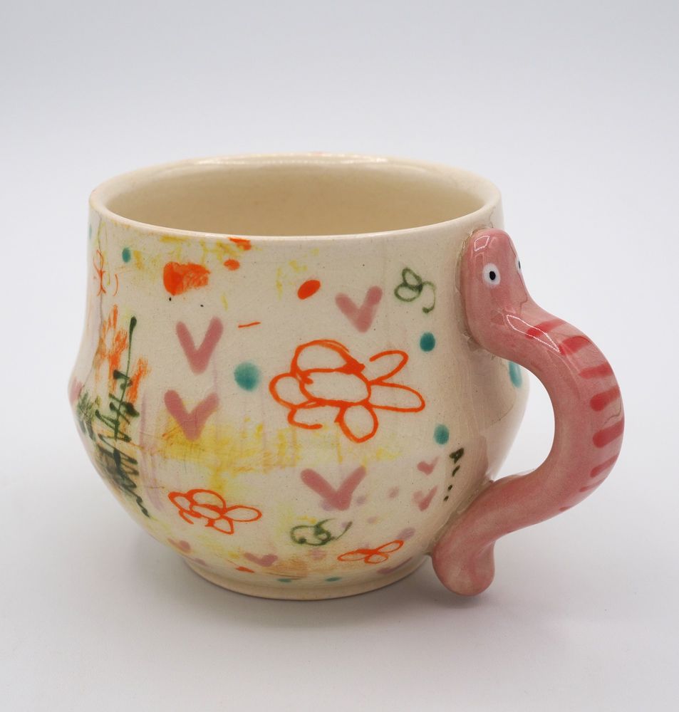 A floral mug with a pink worm as the handle.
