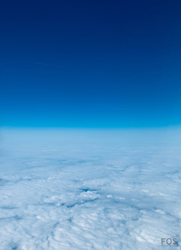 A photo taken above the clouds. The vast blue expanse meet the horizon in the distance… 