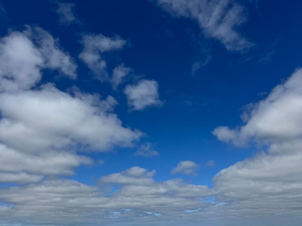A clear blue sky with scattered white clouds, capturing a calm and peaceful morning.