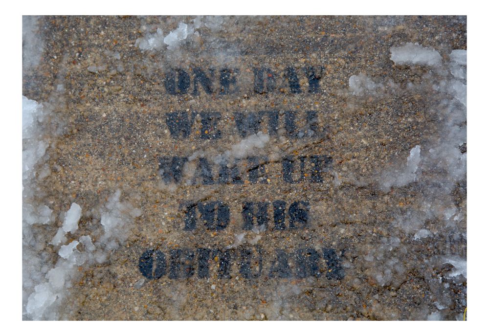 Graffiti on the sidewalk that says, “One day we will wake up to his obituary.”