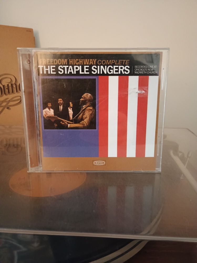 CD case for Freedom Highway Complete by The Staple Singers standing on top of a turn table. 