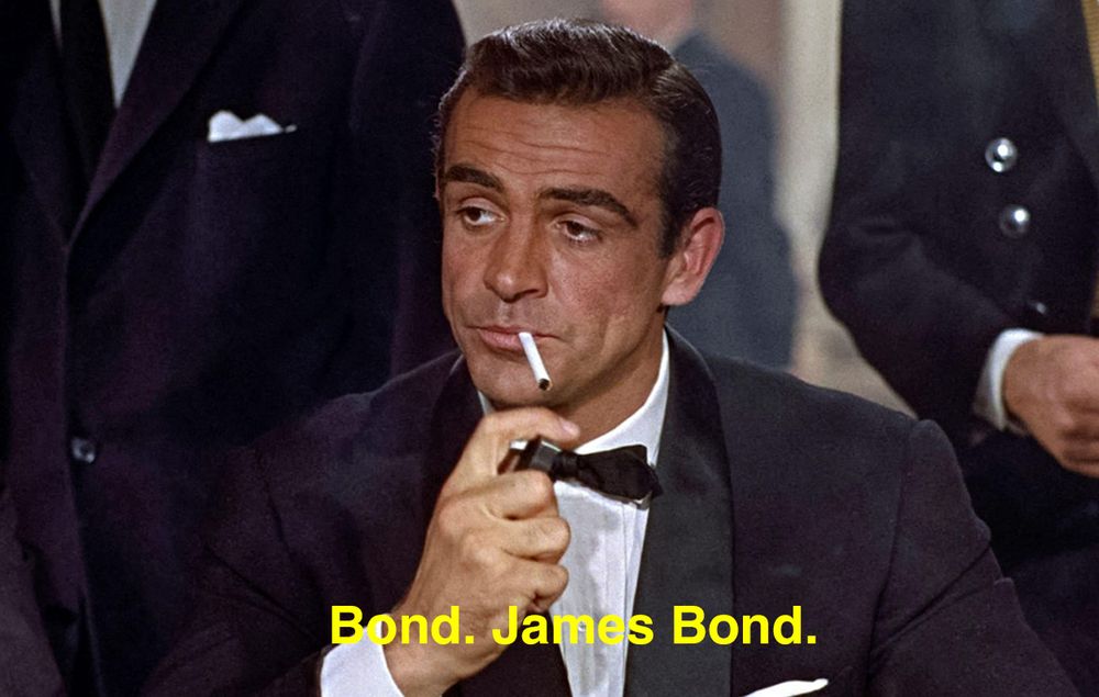 James Bond (played by Sean Connery) at the casino, early in "Dr No". He wears a dinner jacket and black tie, and has a cigarette in his mouth. A subtitle reads, "Bond. James Bond."