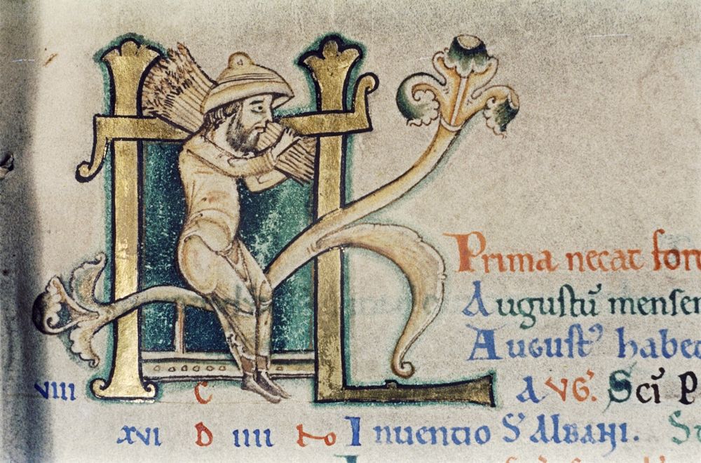 Illustration from a medieval manuscript showing a person wearing a hat and cloak, holding a sheaf of wheat over his shoulder and looking extremely dejected while seated on a decorative letter. Latin text around him relates to the month of August and the labours required.

Bodleian Library MS. Auct. D. 2. 6 from a manuscript by Saint Anselm, Archbishop of Canterbury, 1033-1109. 
https://digital.bodleian.ox.ac.uk/objects/1f893d08-f517-4fa8-9e20-02c225c70b71/