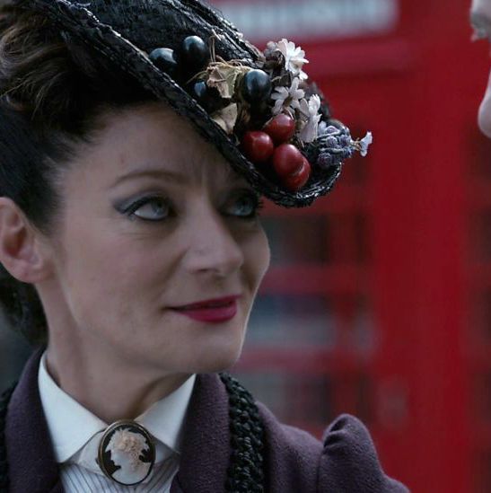 Michele Gomez as Doctor Who's Missy, wearing a heavily decorated hat/fascinator
