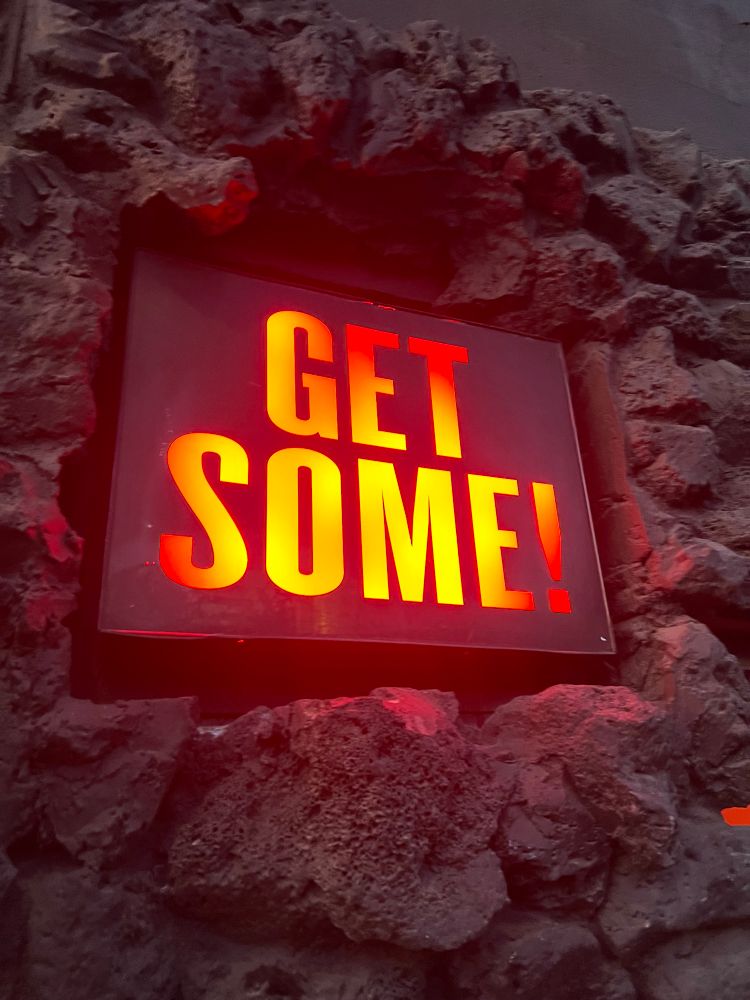 an illuminated sign that says “get some! “