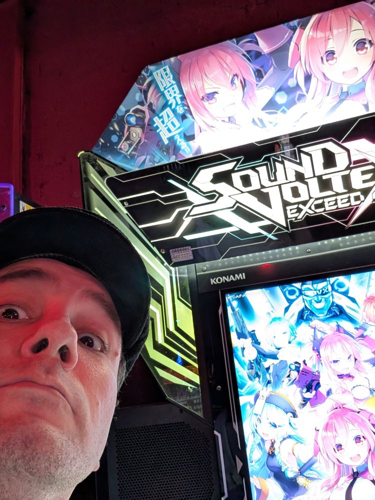 A selfie of a man looking concerned in front of a SDVX machine
