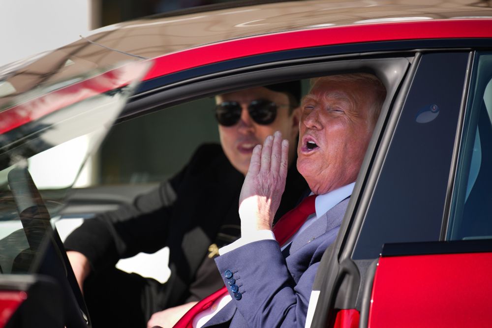 Image of Trump and Elon sitting in a Tesla in a shot reminiscent of the scene in Mean Girls where Regina George rolls up and tells Cady “Get in loser, we’re going shopping.”