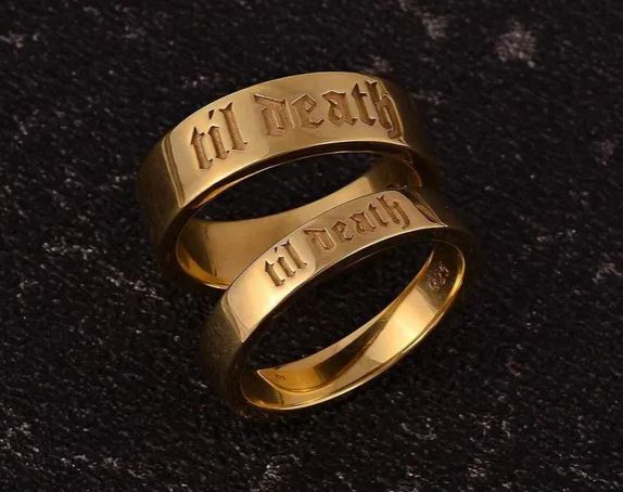 a set of 2 gold bands. one is thinner, the other a bit thicker. both say "til death" in a gothic font.
